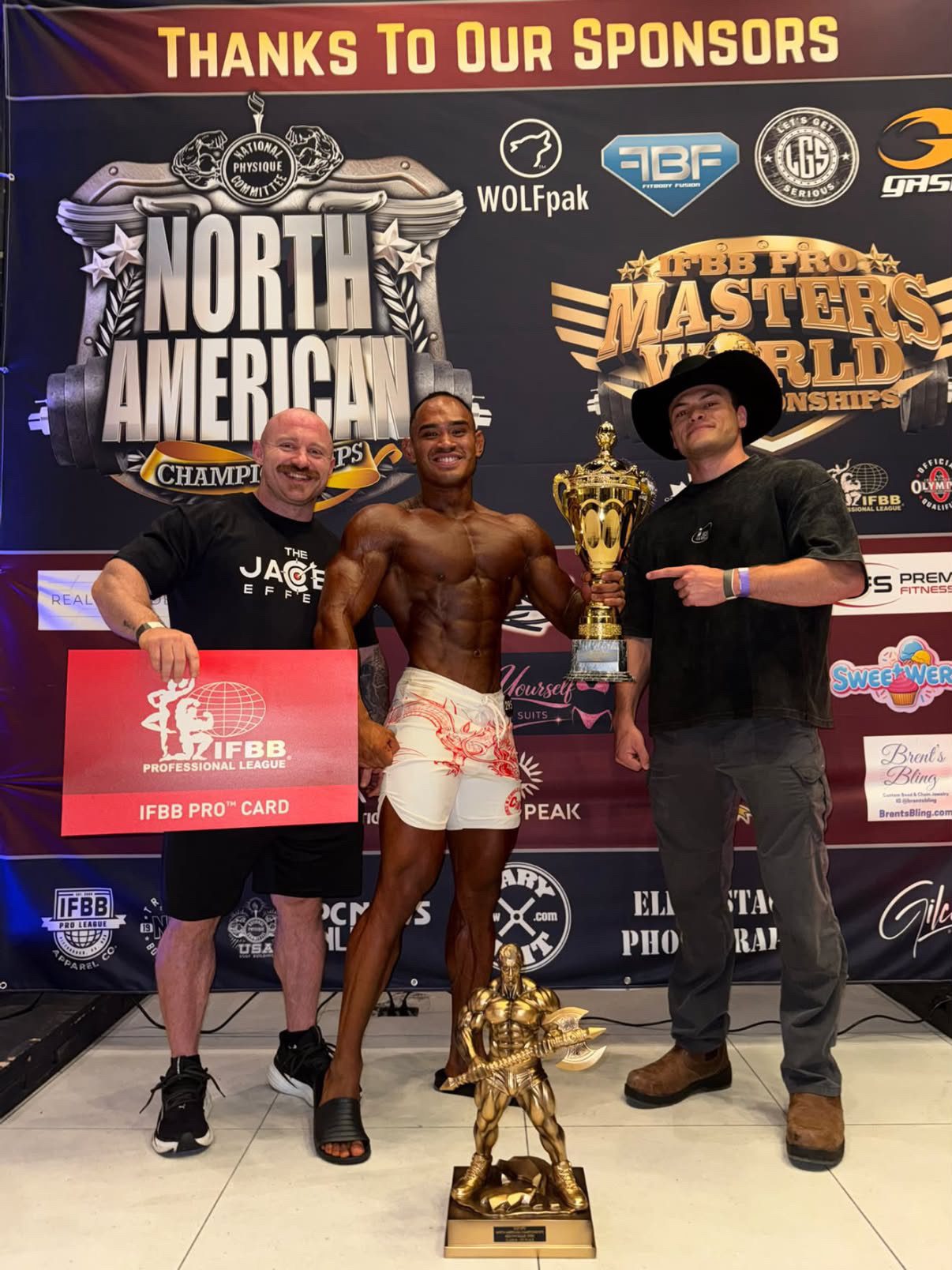 Jake and a coach with a client holding the North American Championships trophy and IFBB Pro Card